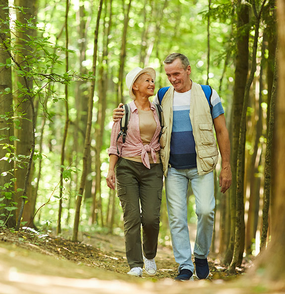 Smiling Senior Couple on Walking Path in Woods Retirement Made Simple Michigan