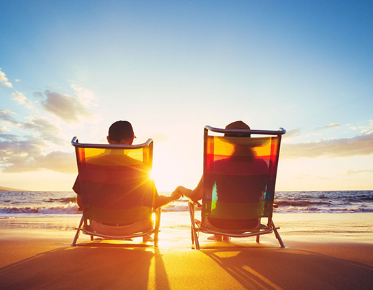 Couple on Beach Sitting in Chairs and Holding Hands while Sun Sets What is Permanent Life Insurance Michigan