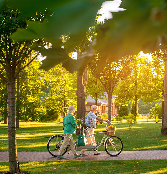 Couple Walking Bikes Beside Them Through Park with Greenery What is Term Life Insurance Michigan