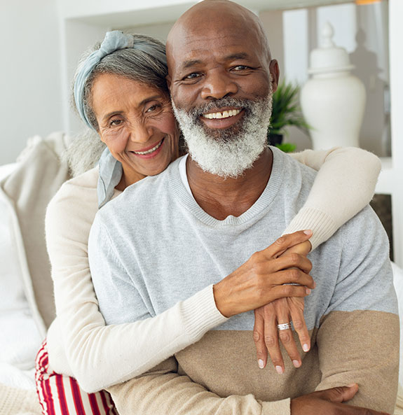 Senior Couple Sitting on Couch with Arms Around Each Other Taxes on Retirement Income Michigan